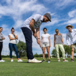 young-man-with-beret-playing-golf-with-golf-club-front-group-people