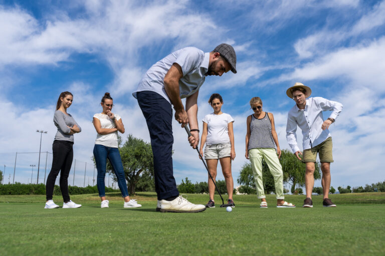 young-man-with-beret-playing-golf-with-golf-club-front-group-people